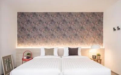 a bedroom with a white bed with a floral wallpaper at China Cozy Asoke in Bangkok