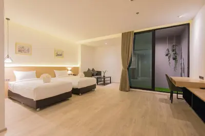a hotel room with two beds and a desk at Madison Bangkok Hotel in Bangkok