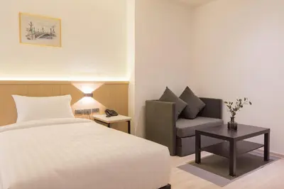 a hotel room with a bed and a chair at Madison Bangkok Hotel in Bangkok