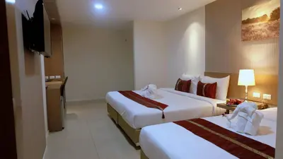 a hotel room with two beds and a television at Baron Residence Bangkok in Bangkok