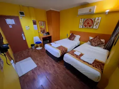 a hotel room with two beds and yellow walls at Wow Guesthouse in Bangkok