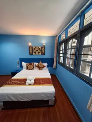 a bedroom with a large bed with blue walls and windows at Wow Guesthouse in Bangkok