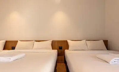 two beds in a room with white sheets at Boxpackers Pratunam in Bangkok