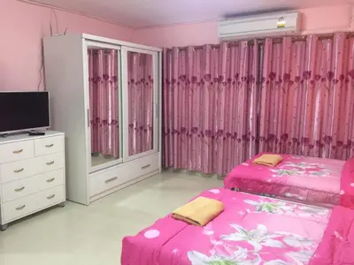 a pink bedroom with two beds and a tv at SK Muang Thong Thani in Bangkok