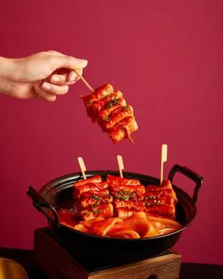 a person holding a piece of food in a pan at Sindhorn Midtown Hotel Bangkok, Vignette Collection by IHG in Bangkok
