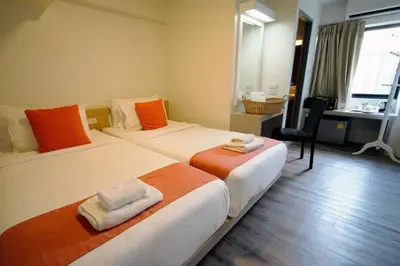 a hotel room with two beds and a desk at Wild Orchid Villa Bangkok in Bangkok