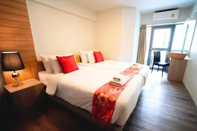 a hotel room with two beds with red pillows at Wild Orchid Villa Bangkok in Bangkok
