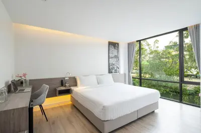 a bedroom with a bed and a desk and a large window at Amarin Hotel Rama 8 in Bangkok