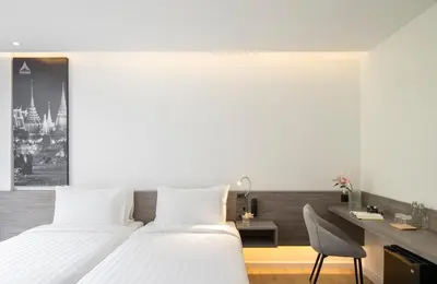 a hotel room with two beds and a desk at Amarin Hotel Rama 8 in Bangkok