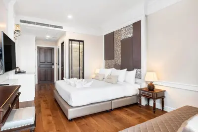 a white bedroom with a bed and a piano at ARUN Riverside Bangkok in Bangkok