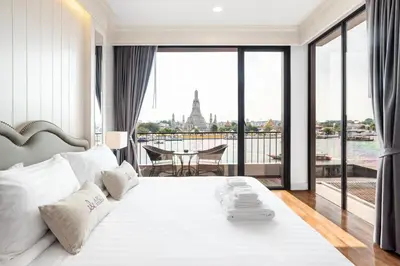 a bedroom with a large white bed with a view at ARUN Riverside Bangkok in Bangkok