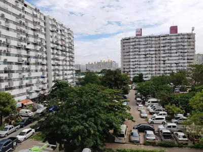 a parking lot with cars parked in front of tall buildings at K.NAT Room service in Nonthaburi