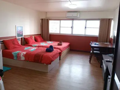 a bedroom with two beds with red pillows and a desk at K.NAT Room service in Nonthaburi