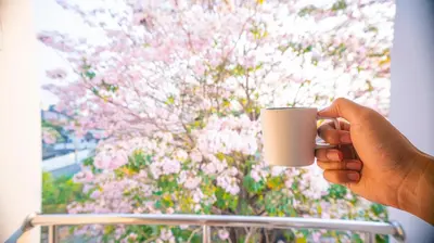 a person holding a coffee cup in front of a flowering tree at The Willing Hotel and Residence in Lak Si