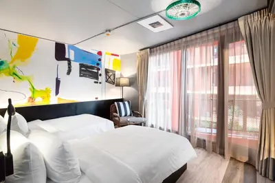 a hotel room with two beds and a window at MeStyle Museum Hotel in Bangkok
