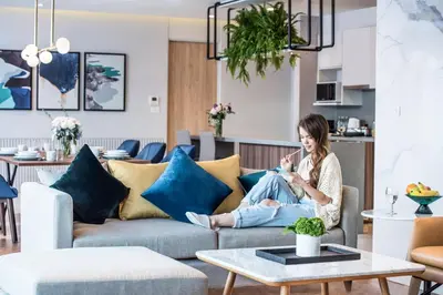 a woman sitting on a couch in a living room at Amanta Hotel & Residence Sathorn in Bangkok