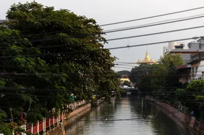 a river with trees and a building in the background at Nappiness Hotel in Bangkok
