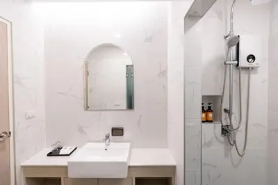 a white bathroom with a sink and a shower at Nappiness Hotel in Bangkok