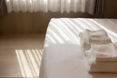 a pile of towels sitting on the edge of a bed at Nappiness Hotel in Bangkok