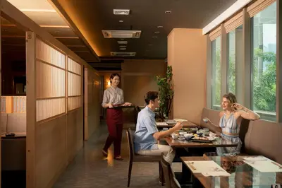 a group of people sitting around a table in a restaurant at Solaria Nishitetsu Hotel Bangkok in Bangkok