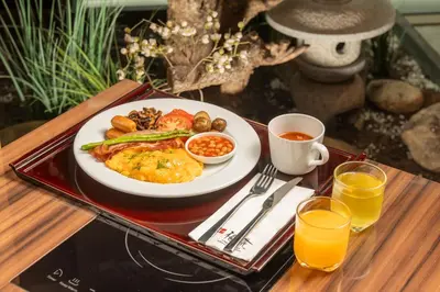 a plate of breakfast food on a tray with orange juice at Solaria Nishitetsu Hotel Bangkok in Bangkok