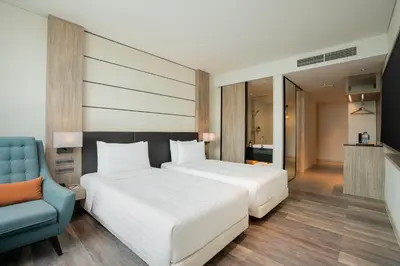 a bedroom with a bed and a blue chair at Solaria Nishitetsu Hotel Bangkok in Bangkok