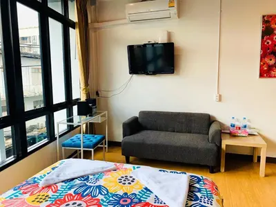 a living room with a couch and a tv on the wall at Daraya Hostel in Bangkok