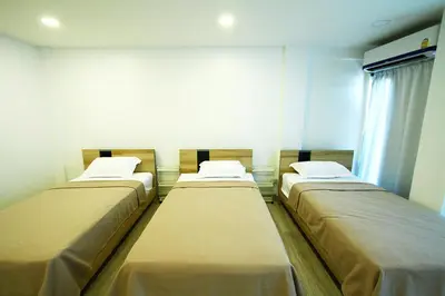 a room with three beds in it with a window at 398 HOSTEL in Bangkok