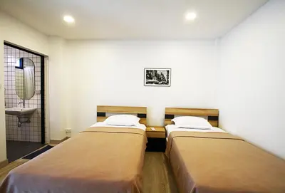 two beds in a room with a bathroom with a sink at 398 HOSTEL in Bangkok