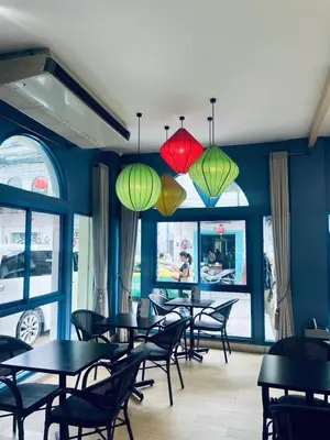 a dining room with tables and chairs and lights at Mangkon Hostel in Bangkok