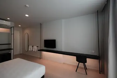a bedroom with a bed and a desk with a television at CHERN Bangkok in Bangkok