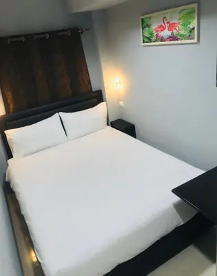 a bedroom with a white bed and a table at HARRYS RESIENDENCE in Bangkok