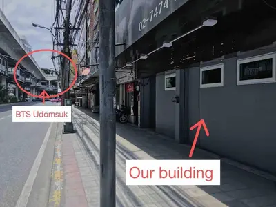 a building with a red sign next to a street at U3 Large 2 Bedroom Full kitchen near BTS Udomsuk in Bangkok