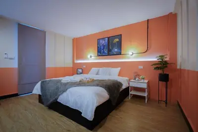 a bedroom with a large bed with an orange wall at Saffron Hill Bangkok in Bangkok