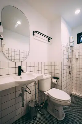 a bathroom with a toilet and a sink and a mirror at Saffron Hill Bangkok in Bangkok