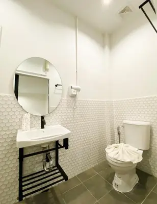 a bathroom with a toilet and a sink and a mirror at Saffron Hill Bangkok in Bangkok