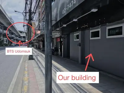 a building with a red sign on a street at U1 Large 2 bed rooms BTS Udomsuk in Bangkok