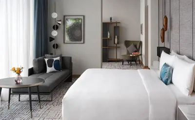 a hotel room with a large white bed and a couch at Kimpton Maa-Lai Bangkok by IHG in Bangkok