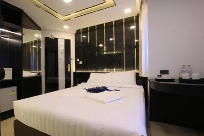 a bedroom with a large white bed with a black wall at Pratunam Atrium Hotel in Bangkok
