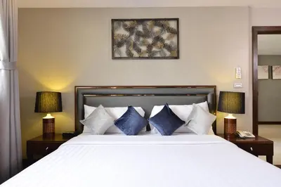 a bedroom with a large white bed with blue pillows at Grand Asoke Suites Boutique Residence in Bangkok