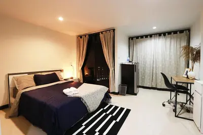 a bedroom with a bed and a desk and a window at Baanrao Bangson in Bangkok