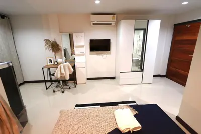 a large living room with a television and a desk at Baanrao Bangson in Bangkok
