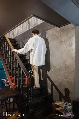 a man walking down a staircase with his shadow on the wall at Tang House in Bangkok