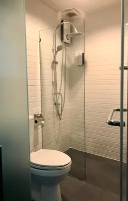 a bathroom with a toilet and a glass shower at Tang House in Bangkok