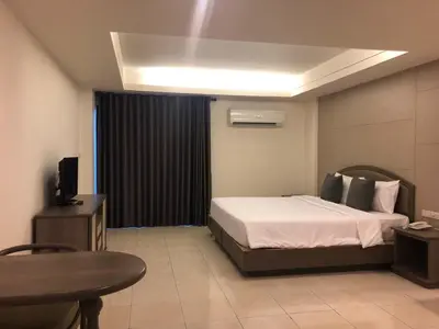 a bedroom with a bed and a table and a tv at Lee Garden Bangkok in Bangkok