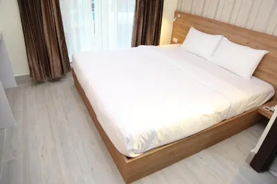 a bedroom with a bed with white sheets and a window at Rose Nana Hotel in Bangkok