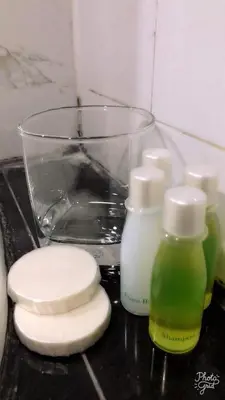 a counter with two bottles of soap and a glass at Rose Nana Hotel in Bangkok