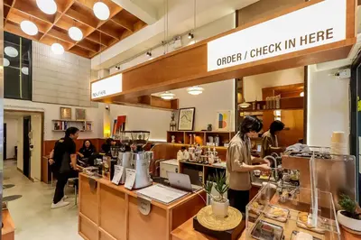 a woman standing at the counter of a coffee shop at StayAt Bedever Bangkok Hotel in Bangkok