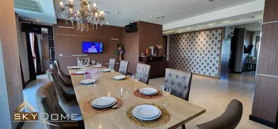 a dining room with a wooden table and chairs at Sky dome resotel - โรงแรมสกายโดม รีโซเทล in Bangkok