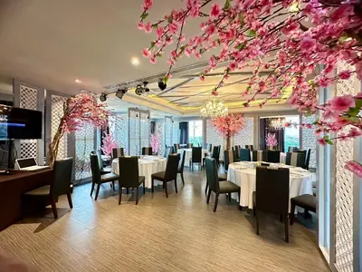 a dining room with tables and chairs and pink flowers at Sky dome resotel - โรงแรมสกายโดม รีโซเทล in Bangkok